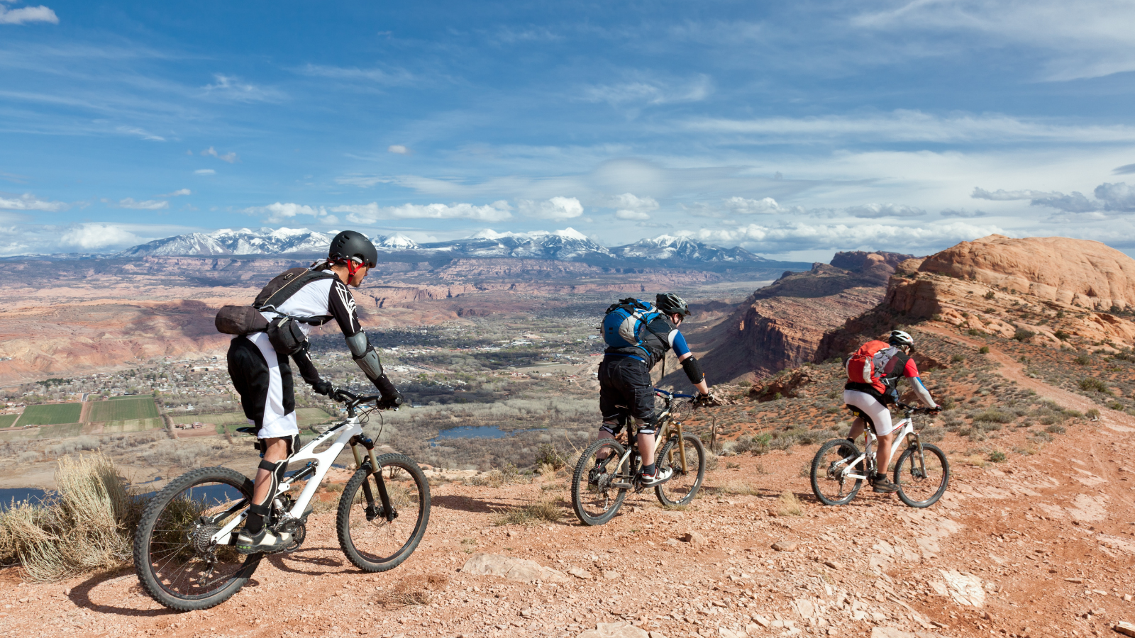 three people biking in the moab red rock formations