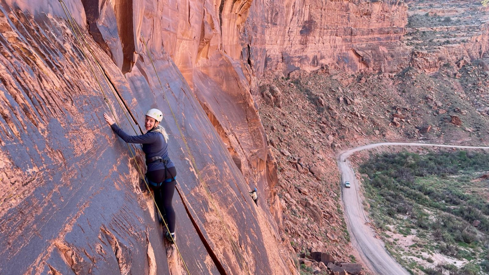 A woman climbing a rock wall in Moab