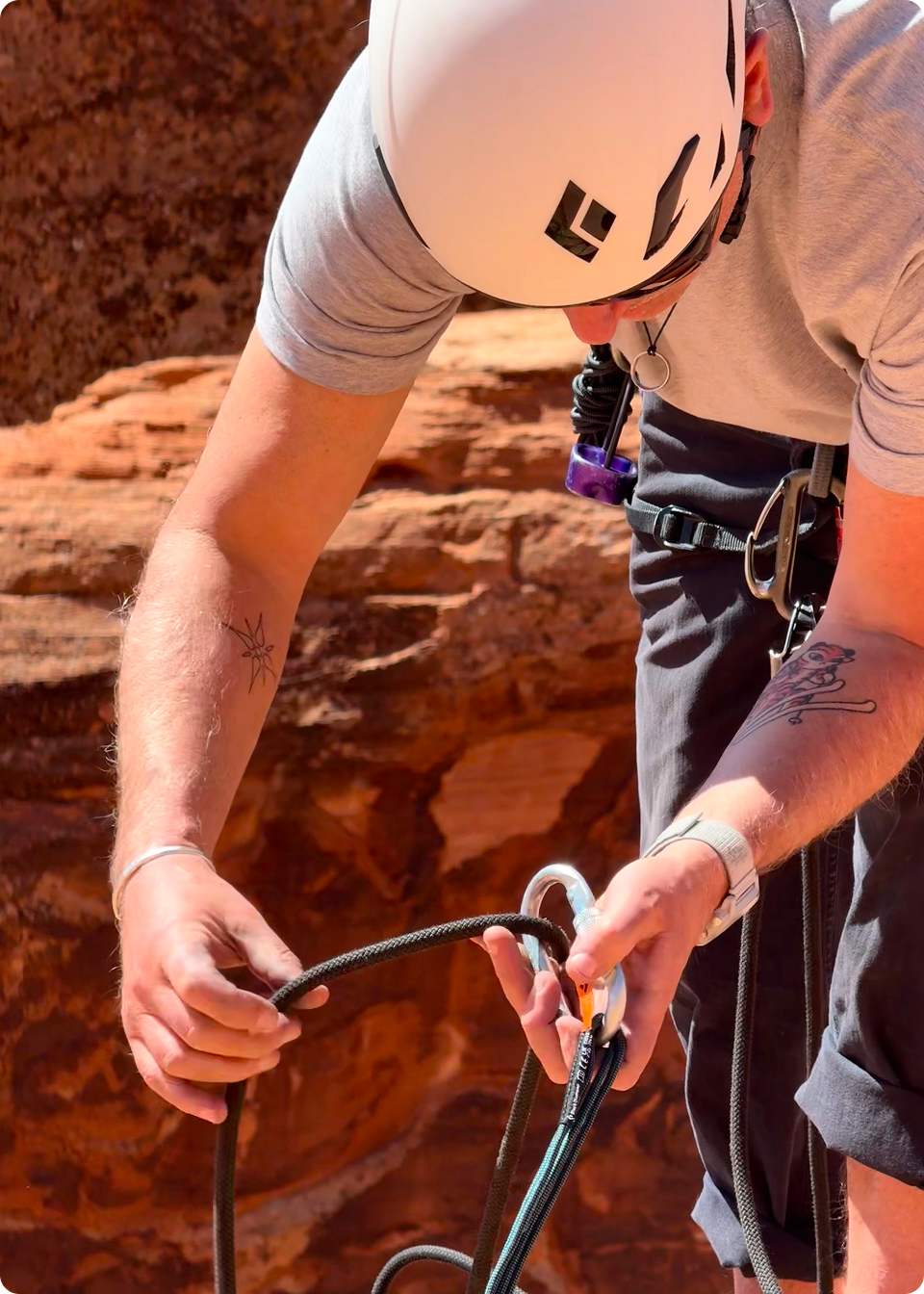 A man in climbing gear demonstrates how to tie knot
