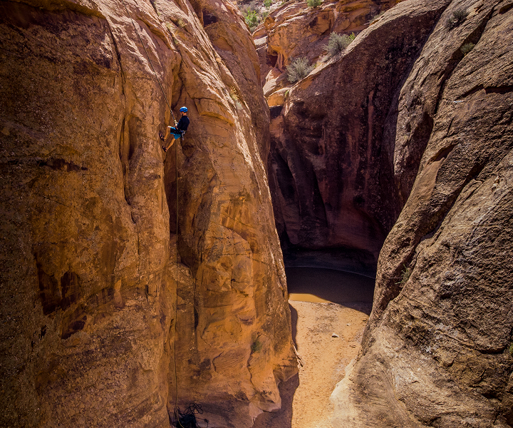 man in blue helmet repelling into canyon