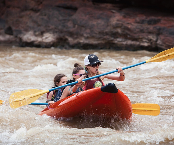 three people in an inflatable kayak in whitewater