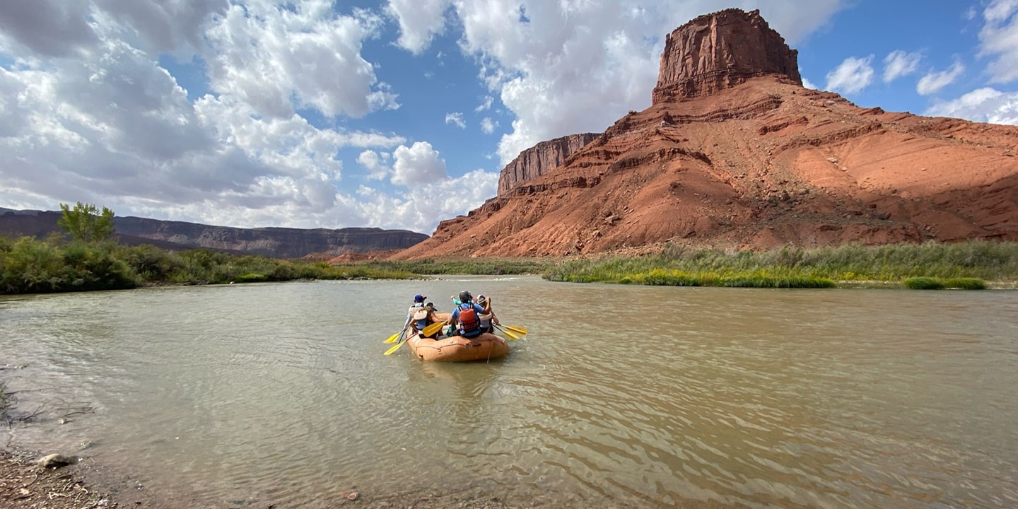 A yellow boat floats down the scenic fisher towers rafting stretch in moab