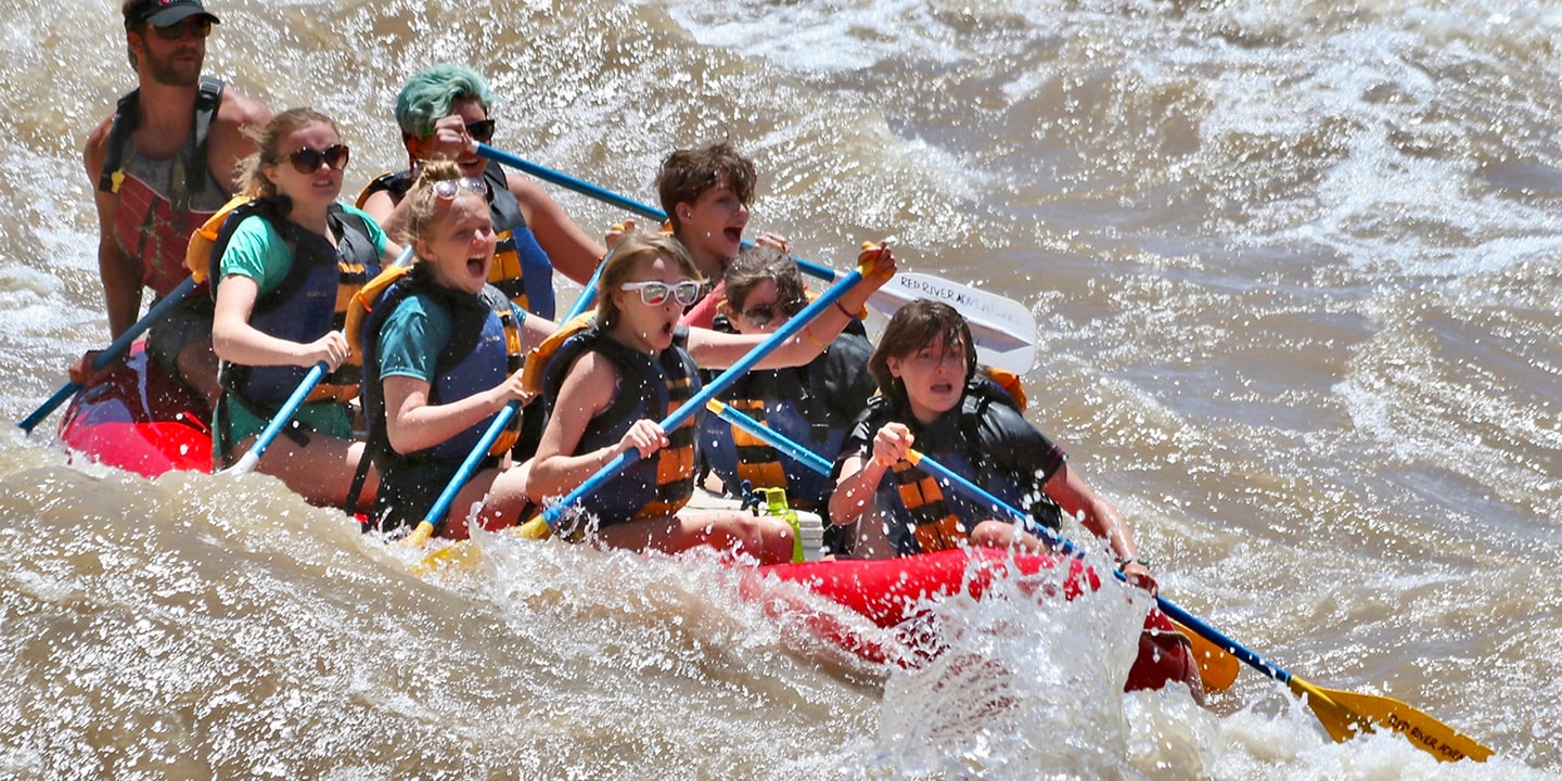 A red raft prepares to paddle through whitewater in moab