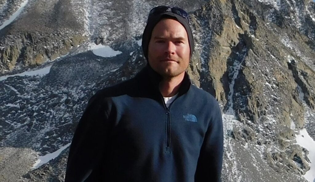 A man in a beanie in front of rocks