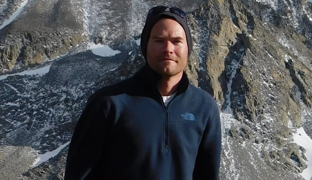 A man in a beanie in front of rocks