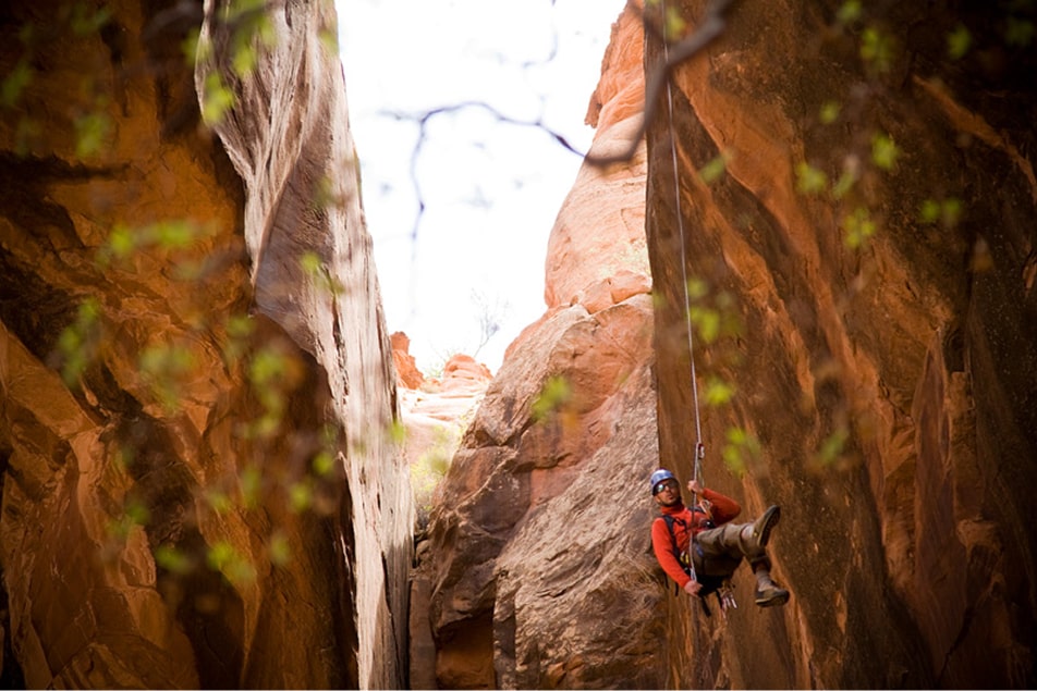 A man rappels down the narrow morning glory arch in moab