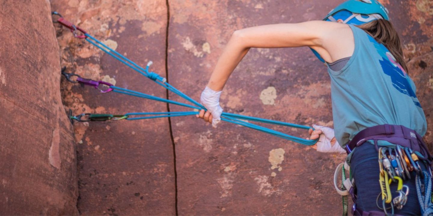 A woman practices placing trad climbing equipment