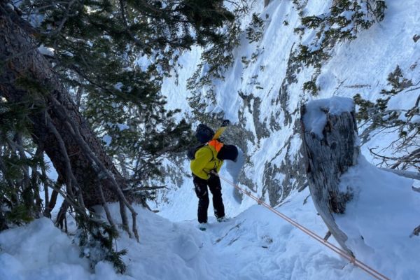 A person taking a Ski Mountaineering Course rappels down a snowy area