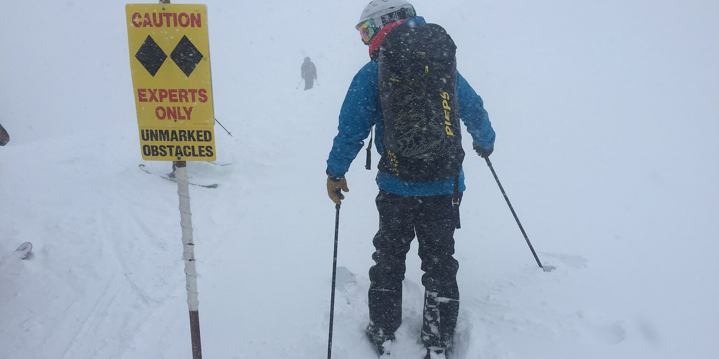 A man skis past an experts only sign