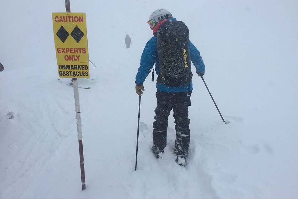 A person skis past an experts only sign