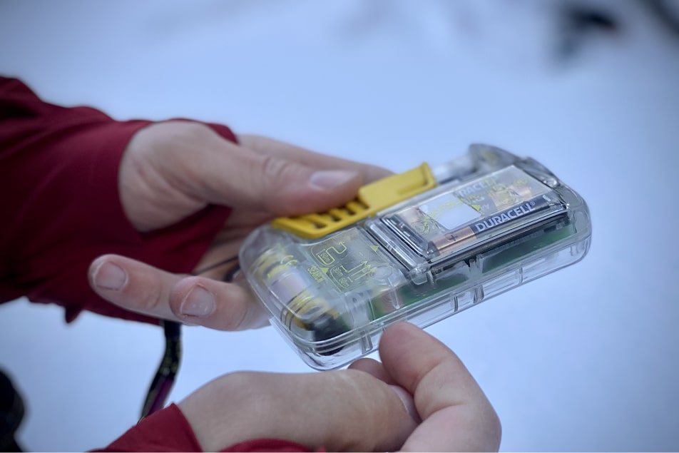 A person hold up a beacon during an avalanche training course