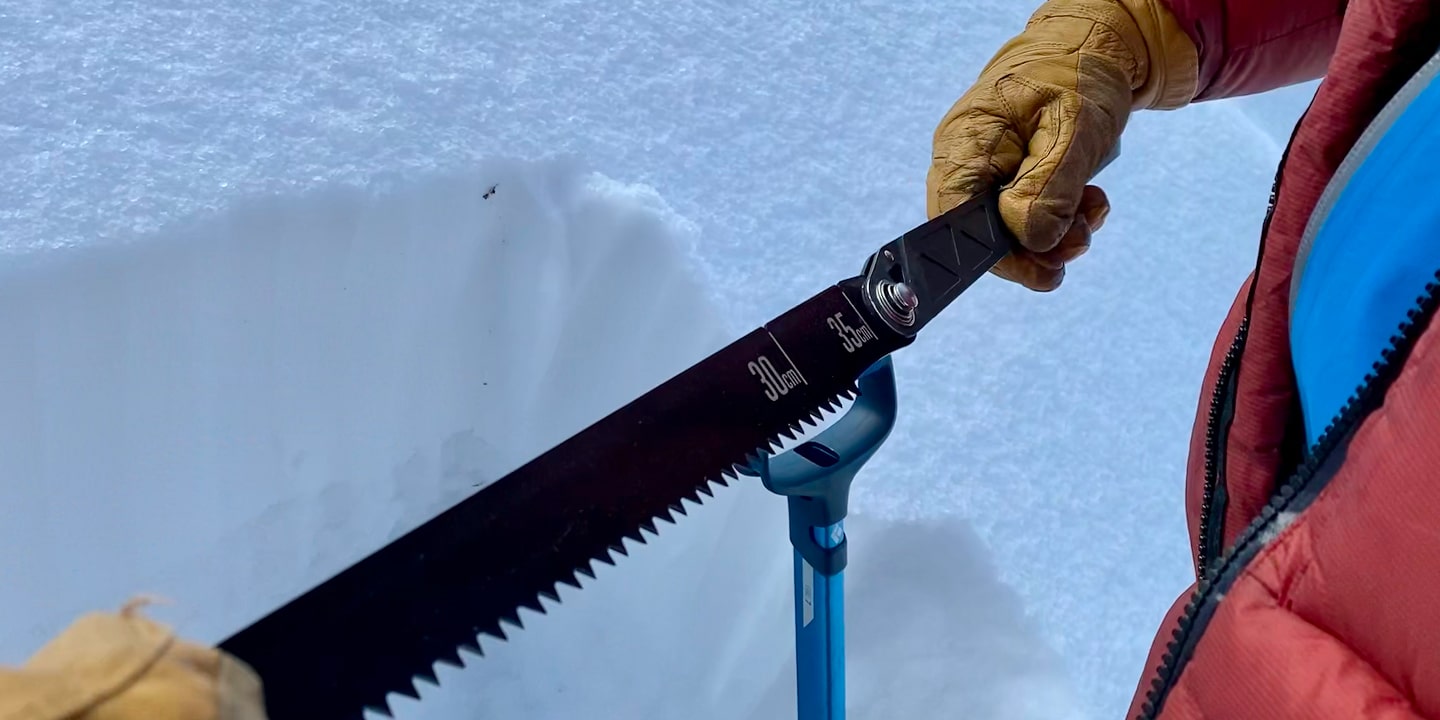 A person in the snow holds and snow axe