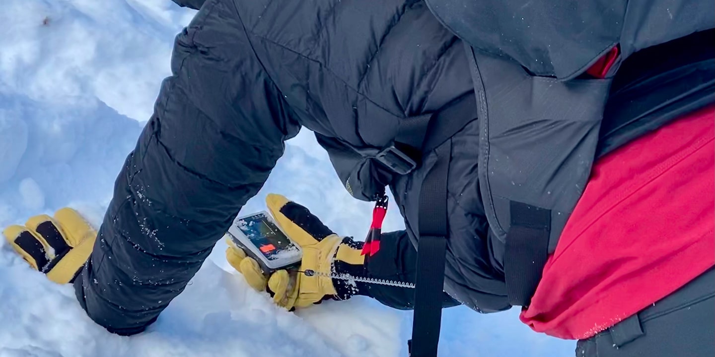 A person practicing using their beacon during avalanche training