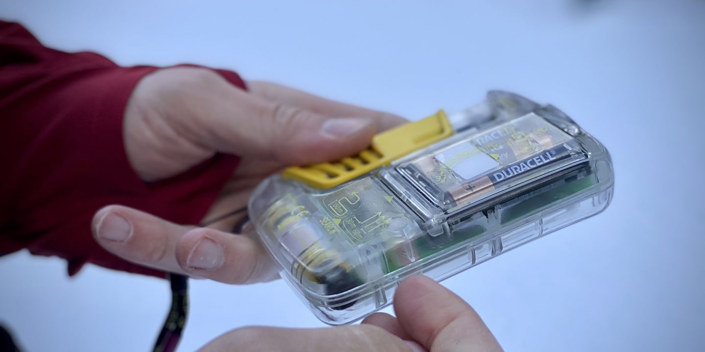 A person holds a beacon while practicing avalanche training