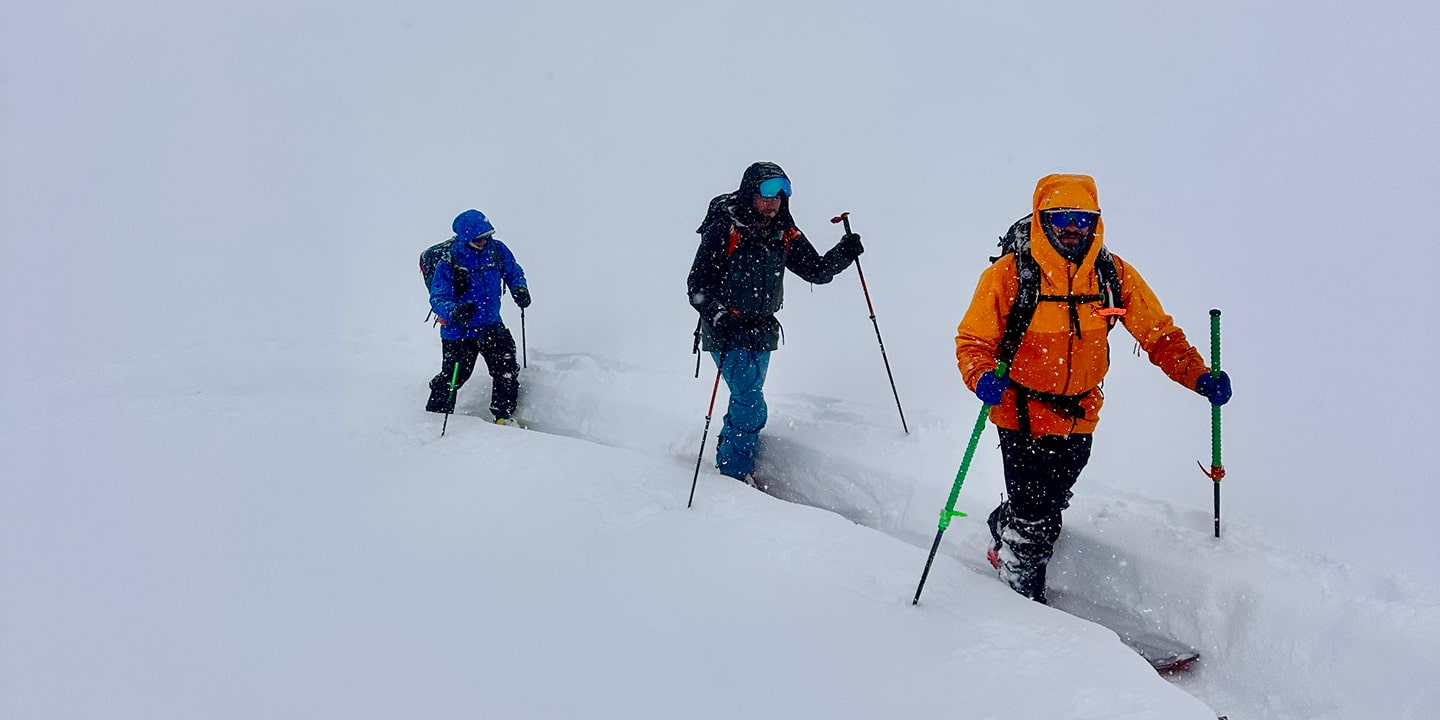 three people backcountry skiing with a guide
