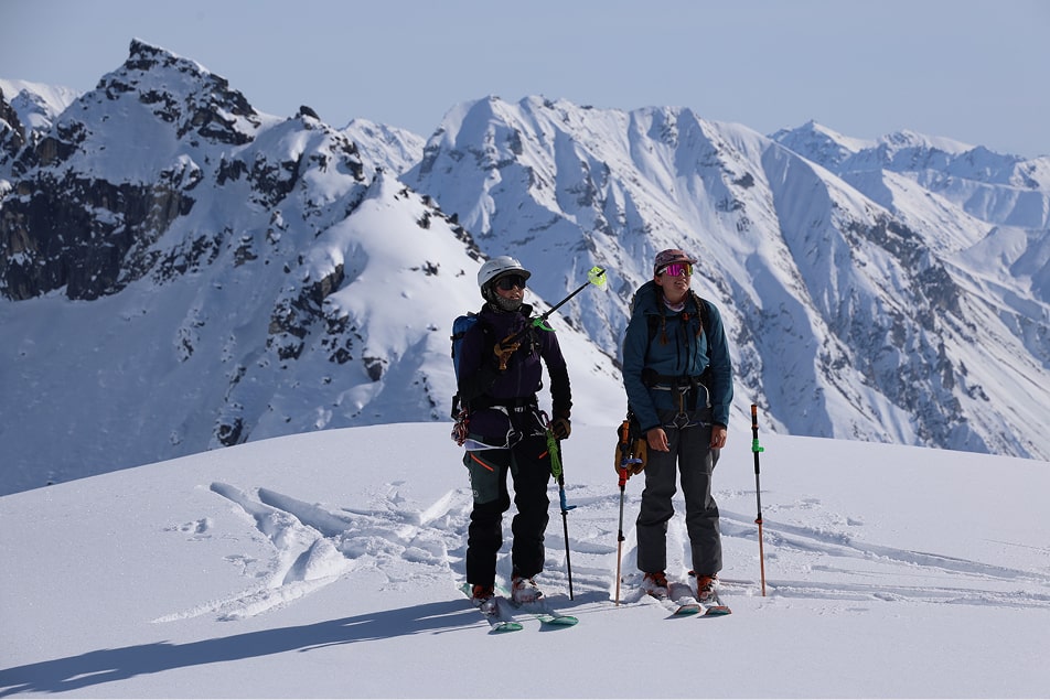 two people on a mountain ridge backcountry skiing