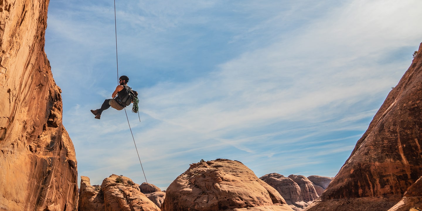 A person rappels down bow and arrow canyon in moab