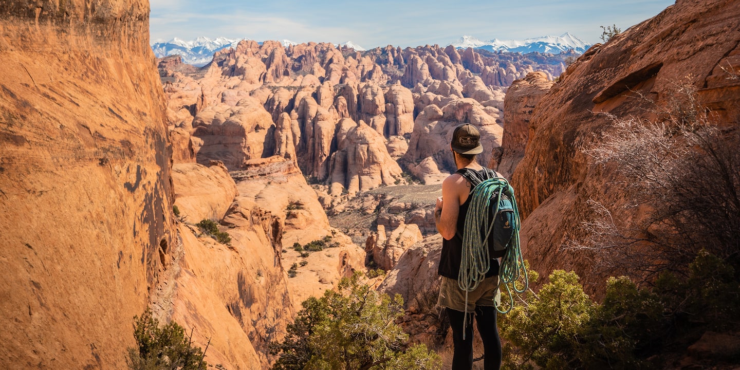 A man looks into the distance in moab carrying a rope