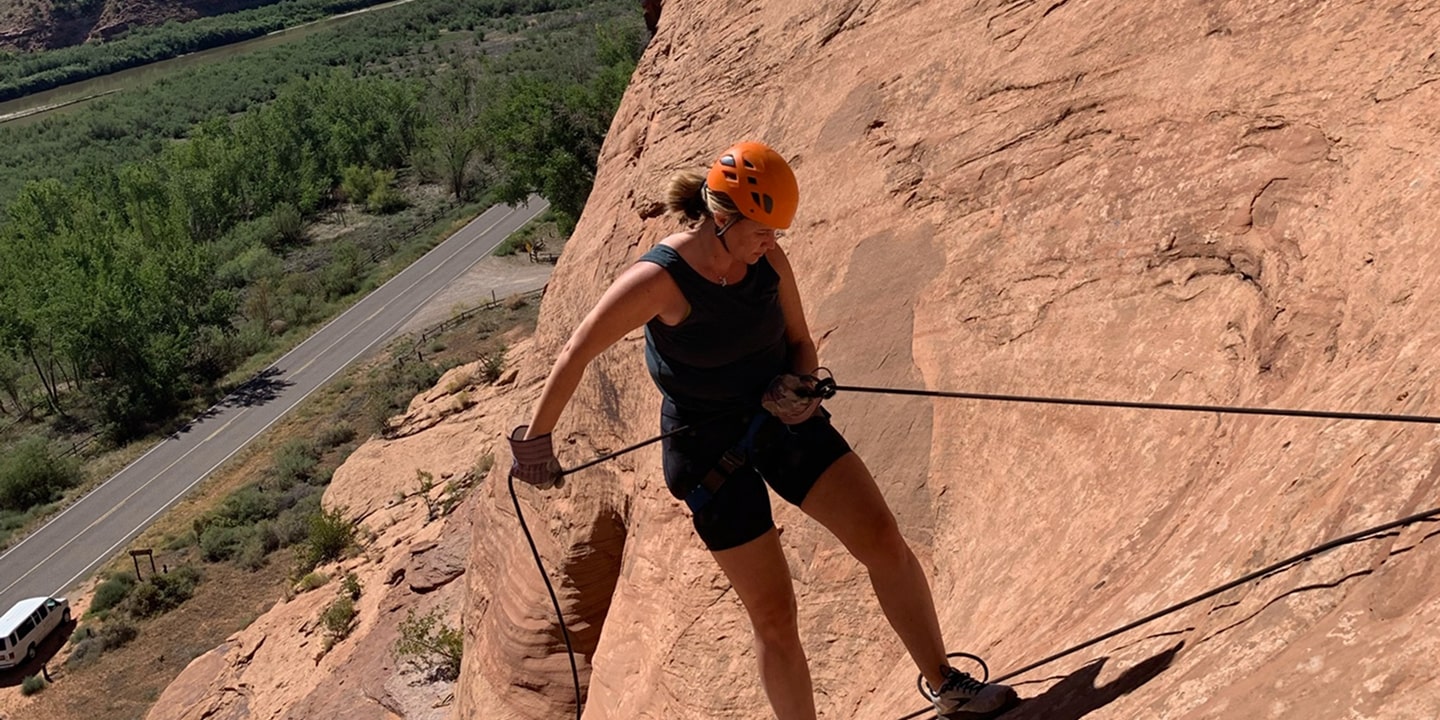 A woman rappels down a red rock formation