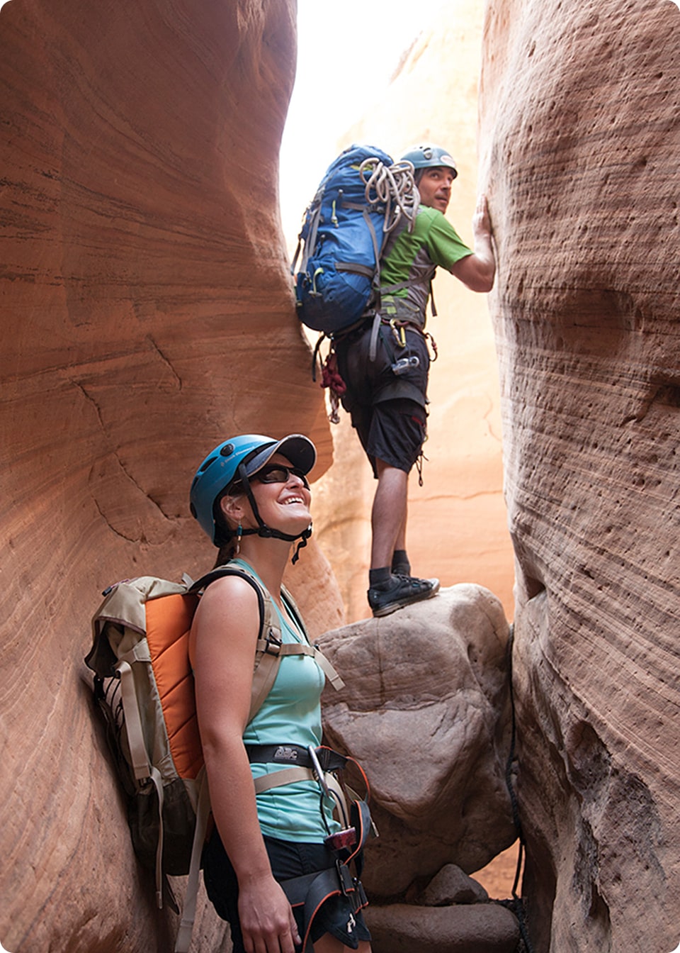 A man and women walk through a slot canyon while canyoneering in moab