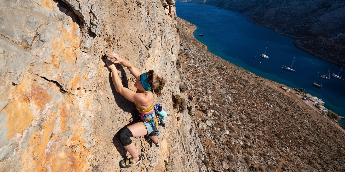 women top roping a climbing route above water