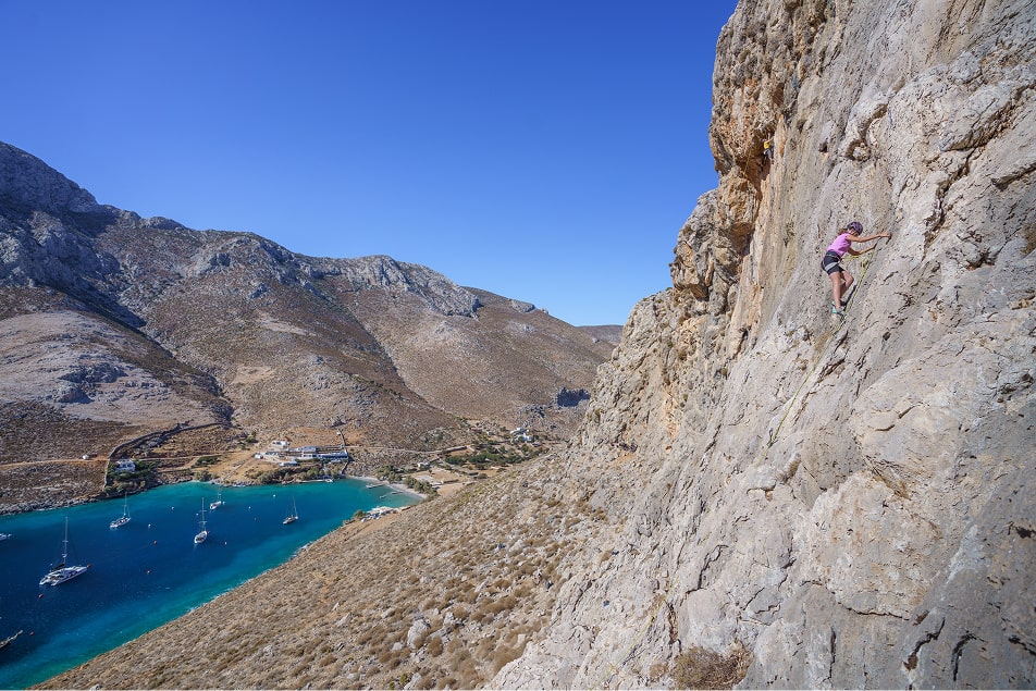 woman rock climbing on large rock face above the waters near Kalymnos