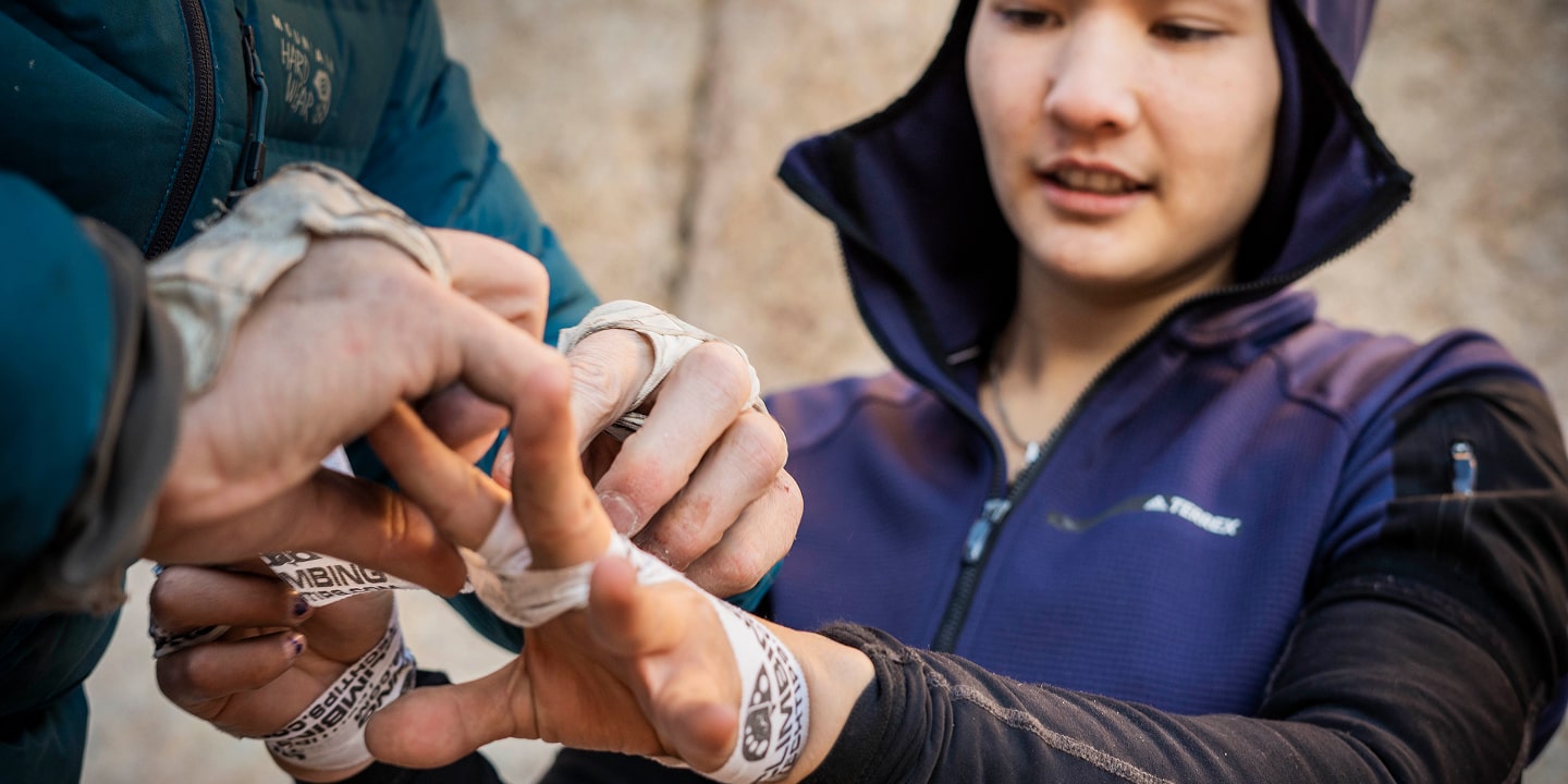 A woman gets help putting tape on her hands while at crack camp