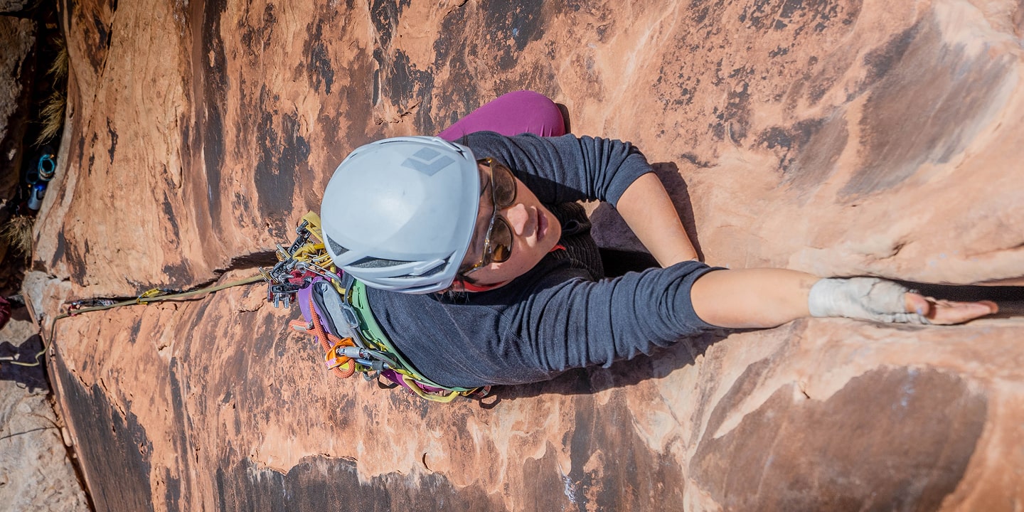 A woman climbing has both hands in the rock's crack