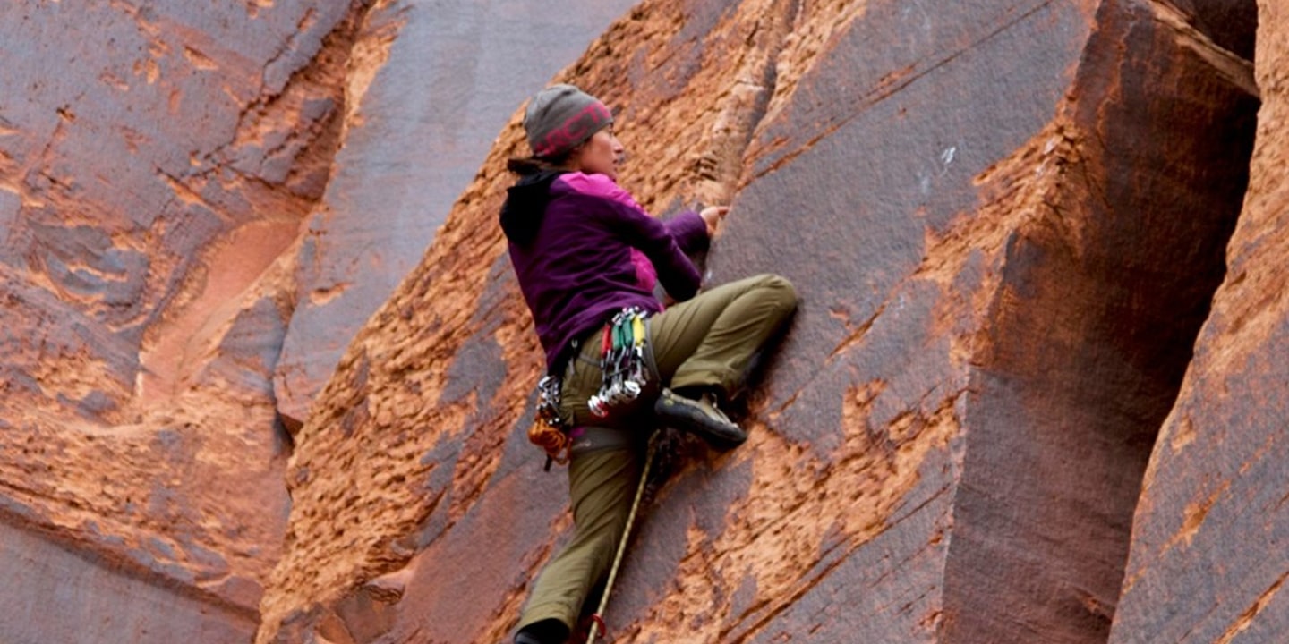 A woman climbing a crack in indian creek in moab