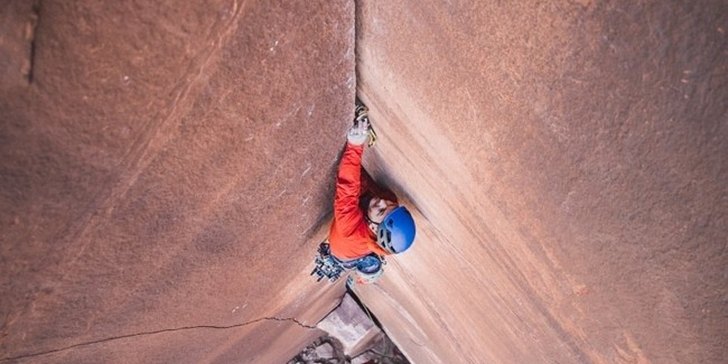 A man in a red shirt crack climbing in indian creek moab