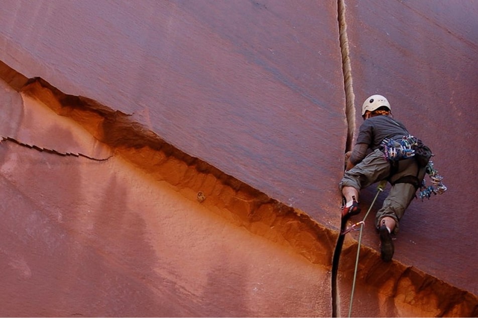 A man climbs a crack in the popular indian creek rock climbing area in moab