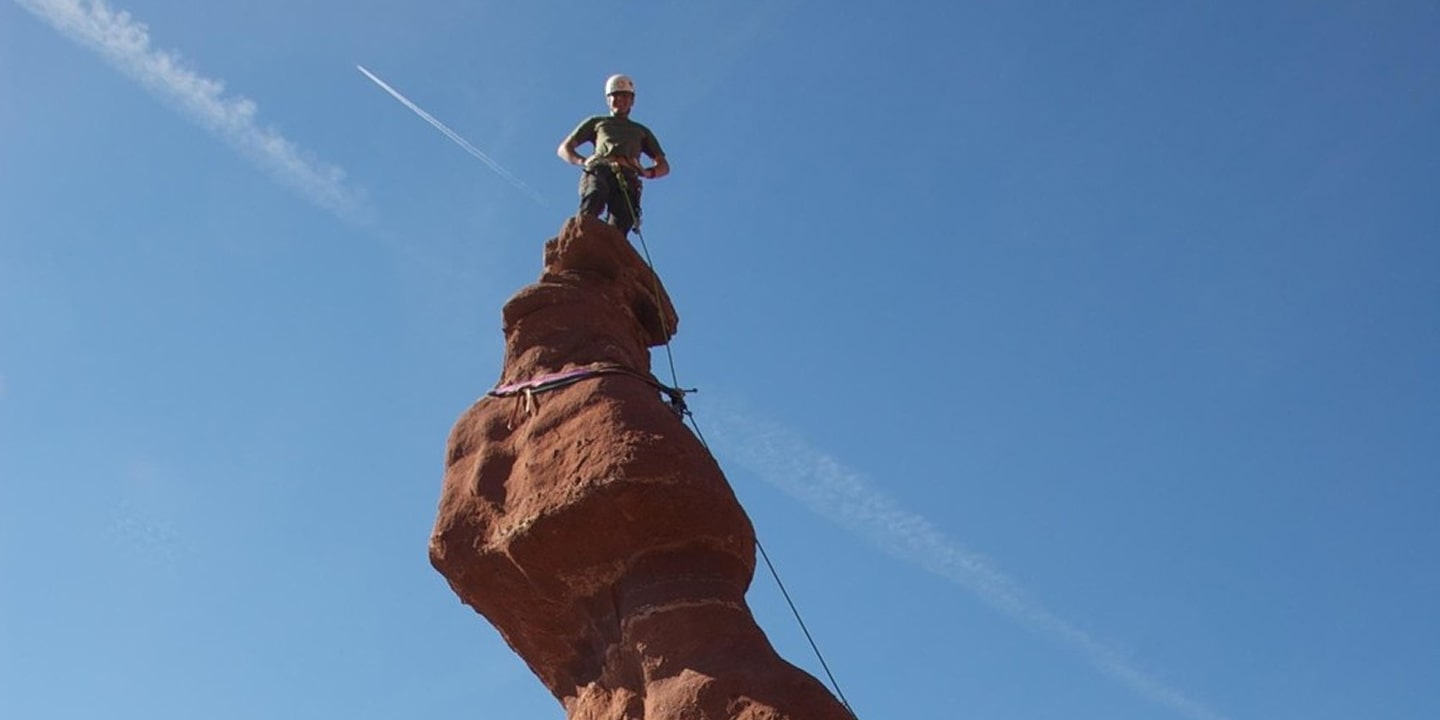 A person stands on top of fisher towers ancient art rock formation