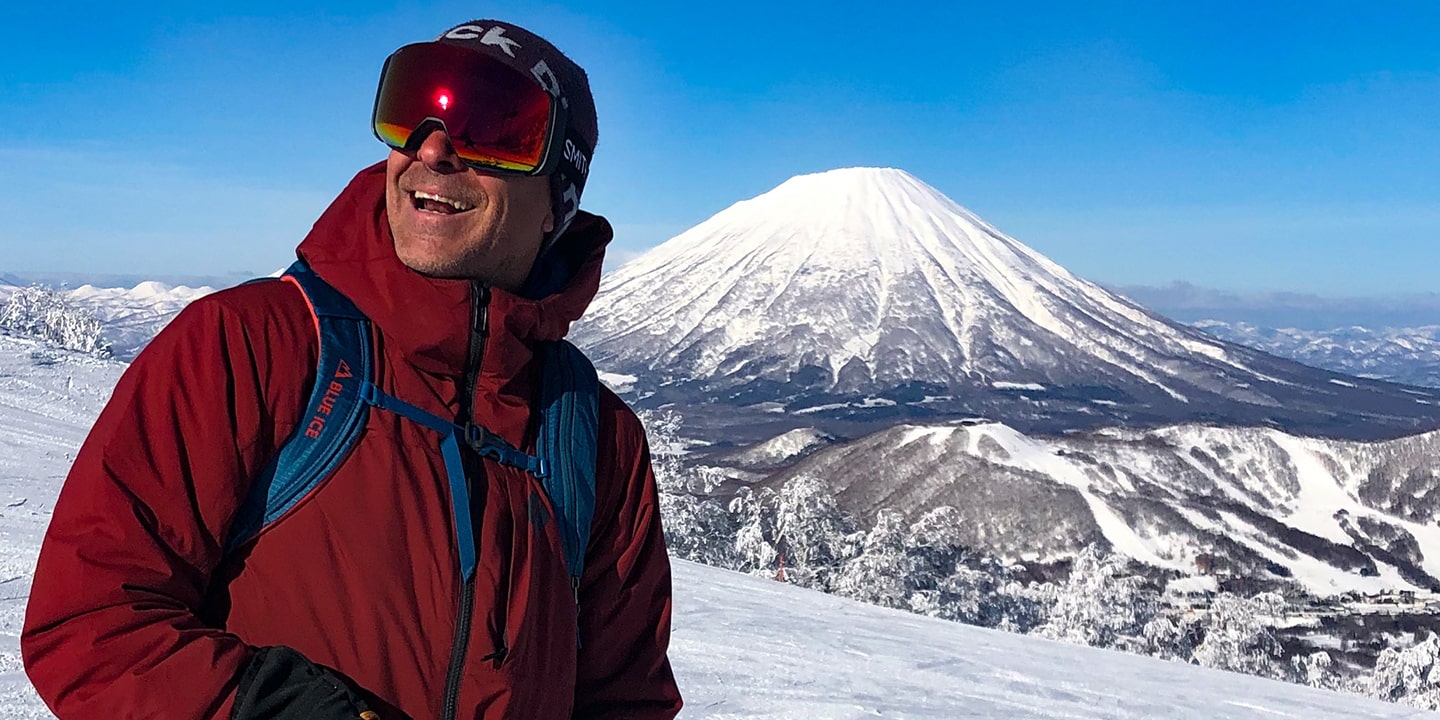 A man in ski gear in front of a volcano in hokkaido