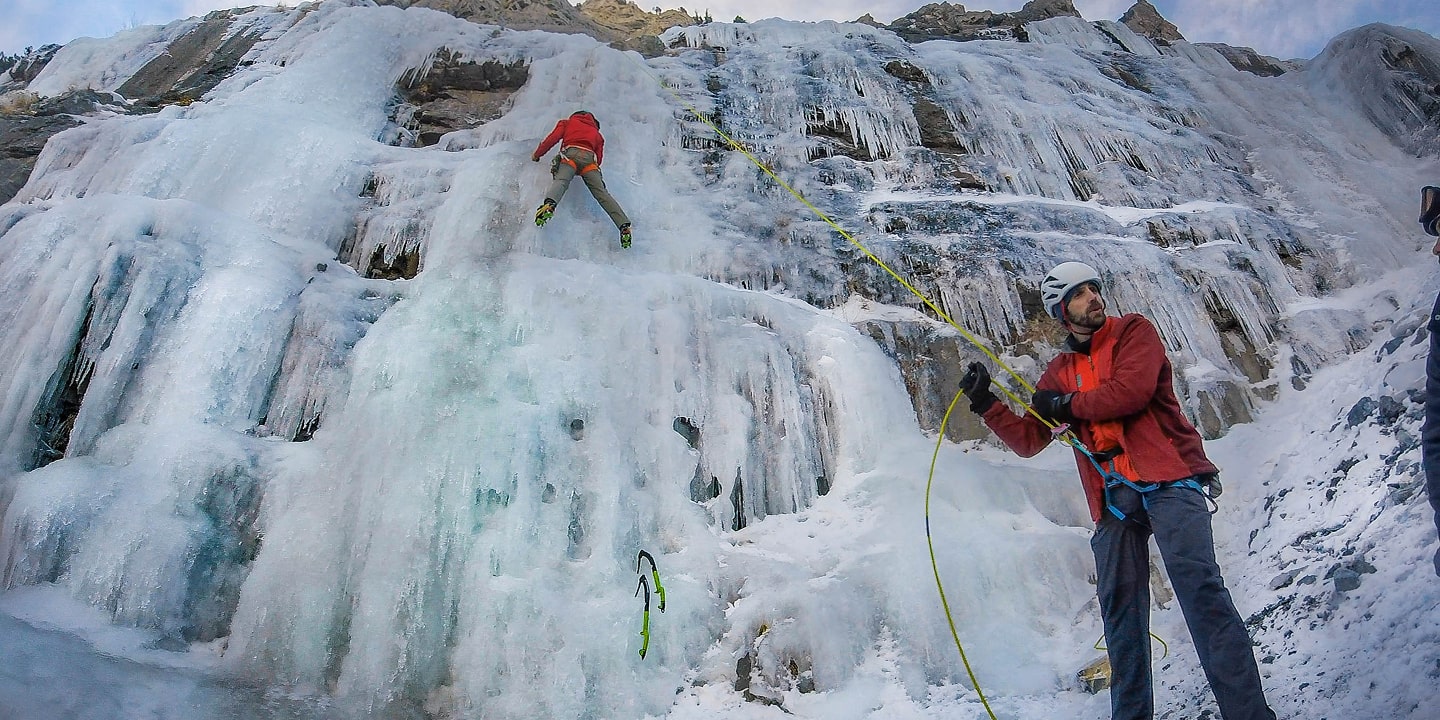 A person belays another person who is ice climbing