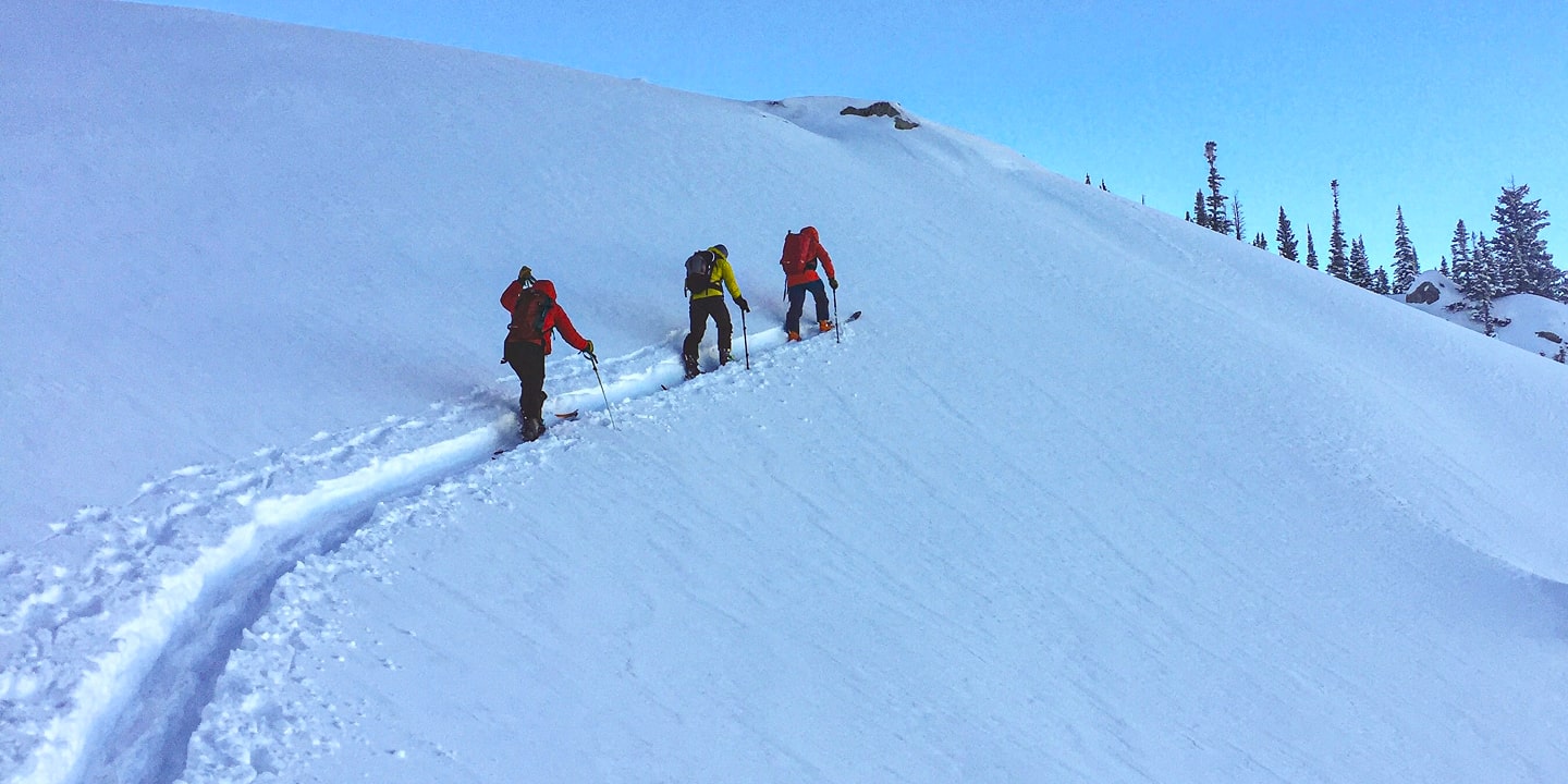 A group of people skin up a mountain single file