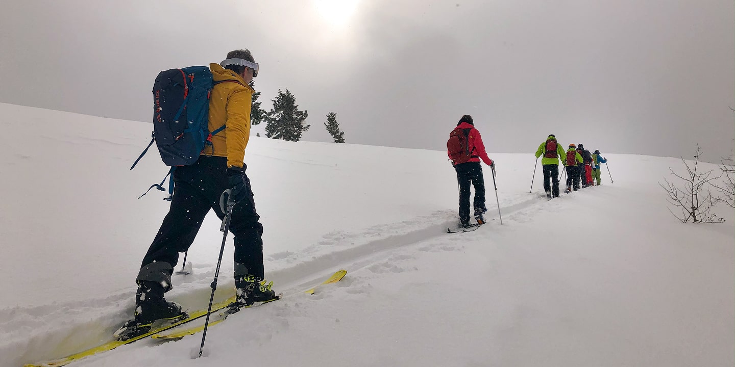Three people skin up a mountain on skis