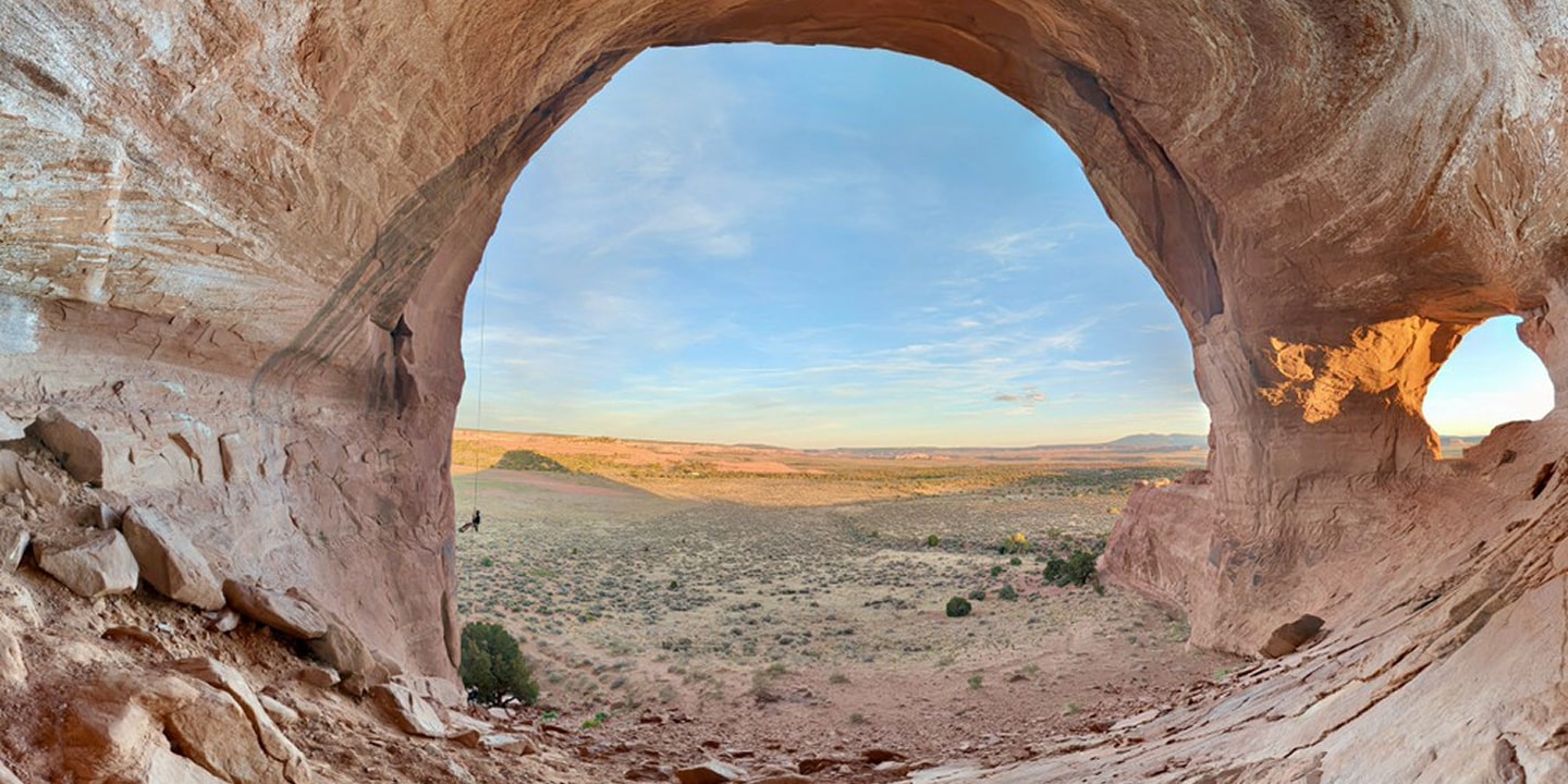 A person rappels down looking glass arch in moab