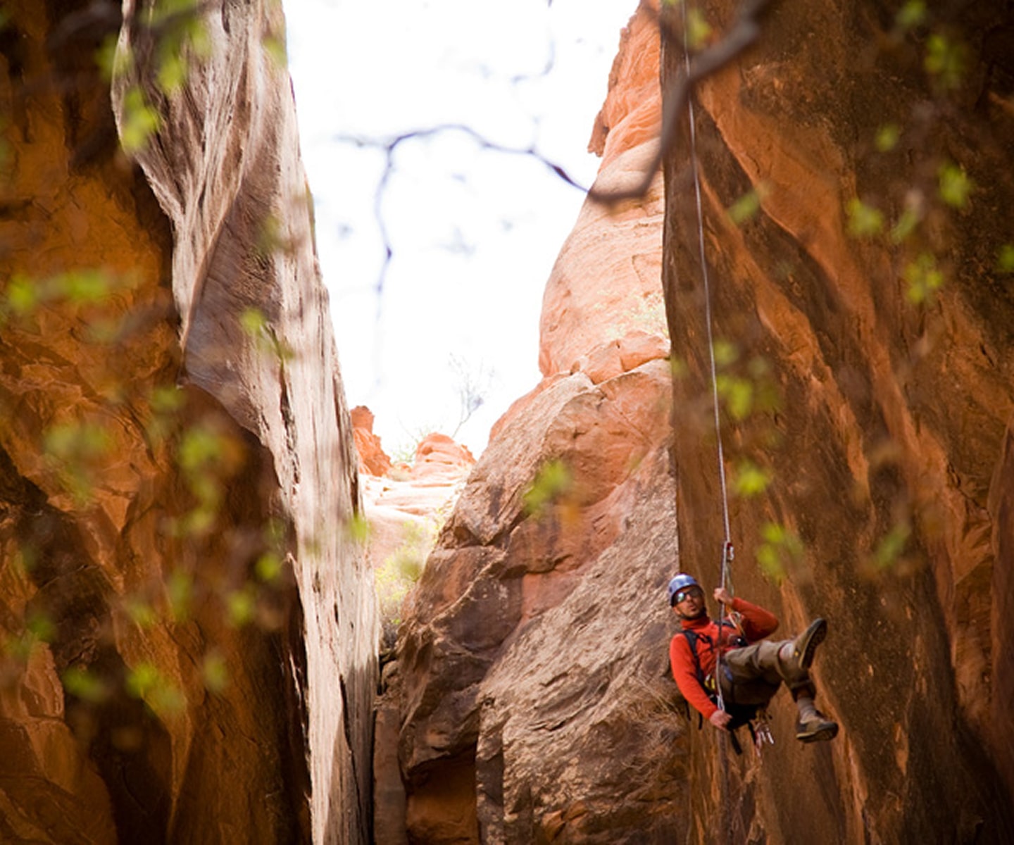 man repelling through red rock formations