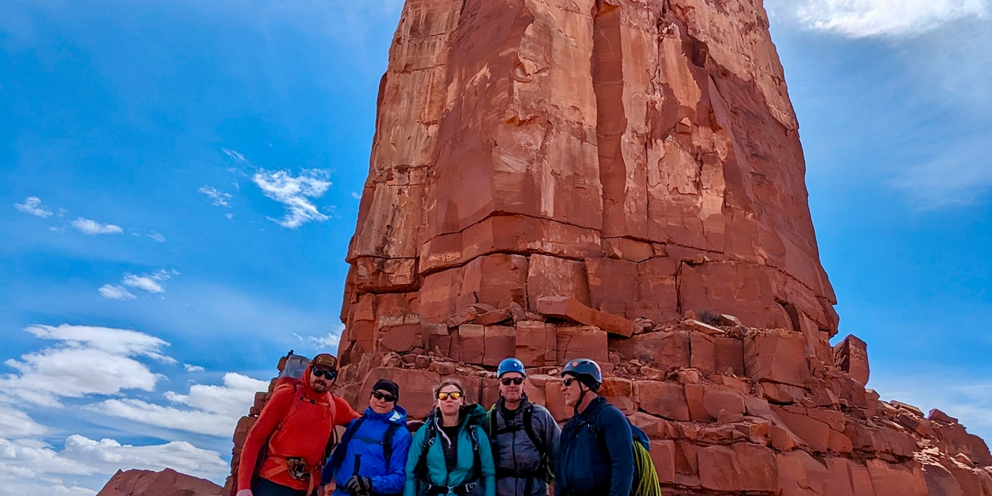 A group of people stand infront of a red rock formation