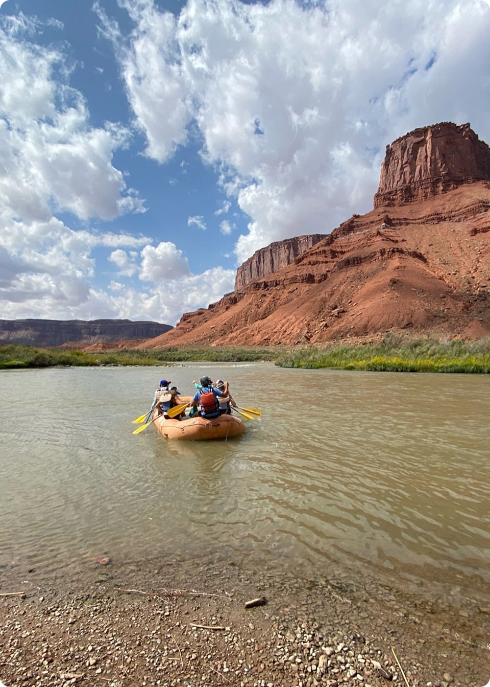 People in a yellow raft float on the scenic colorado river in moab
