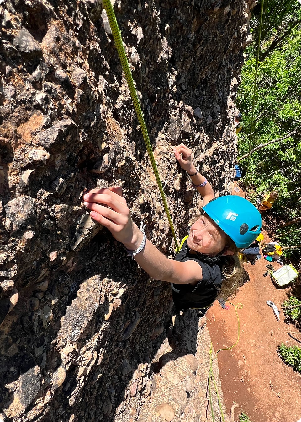 A girl in a blue helmet rock climbing in Utah