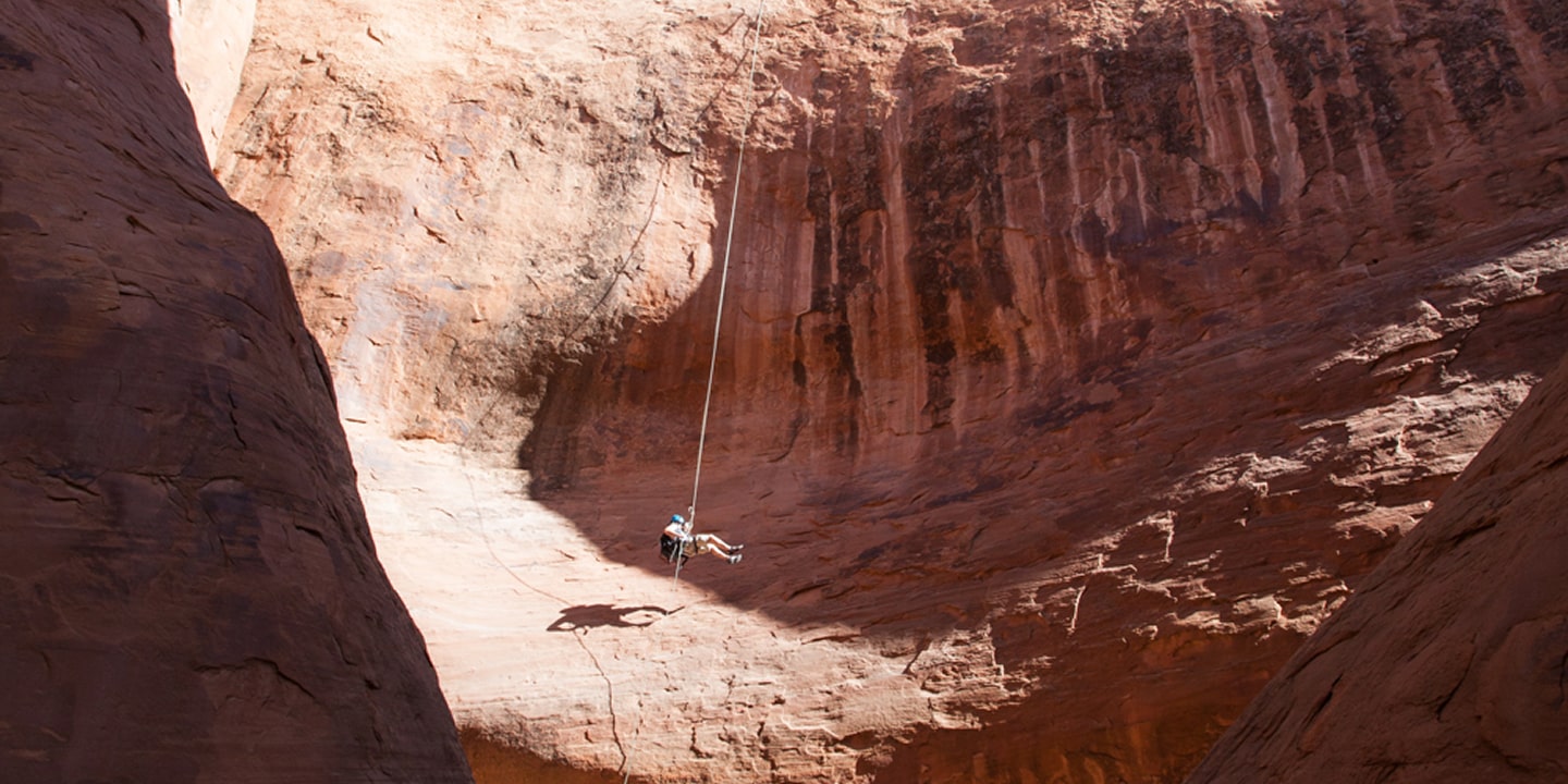 A man in the middle of a long rappel while canyoneering