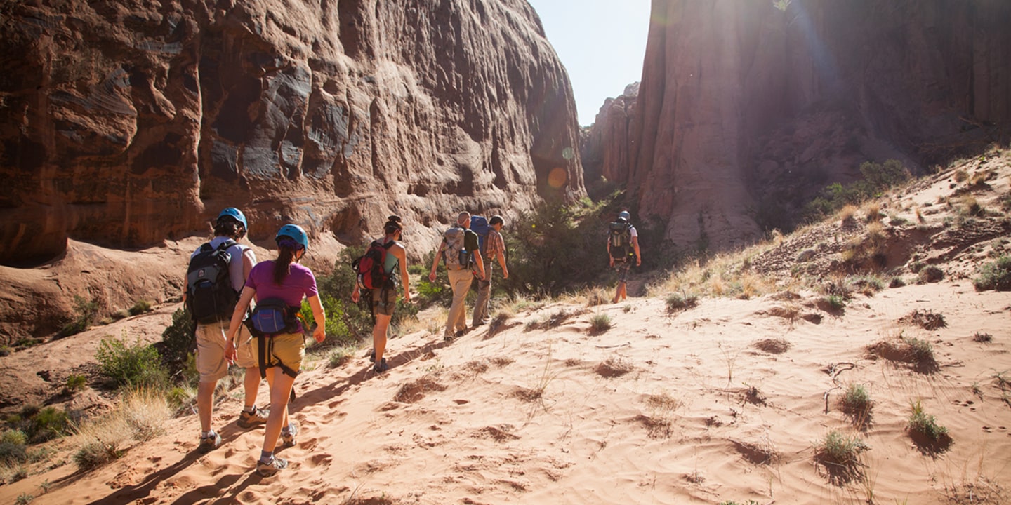 A group of people hike to the rock of ages canyoneering area in moab
