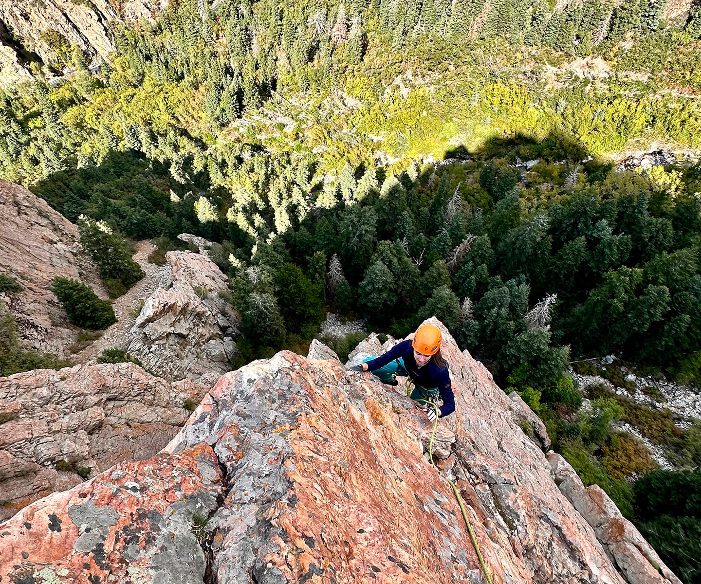 women wearing an orange helmet climbs a rock spine