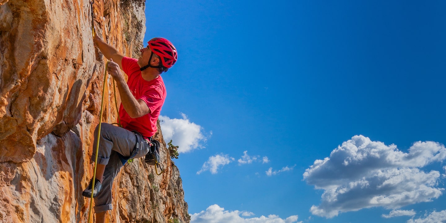 man lead climbing a rock route on Sicily rock climbing trip