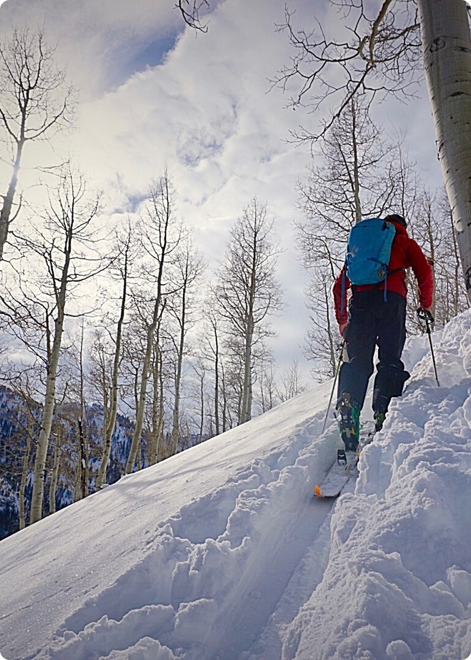 A man skins up a snowy mountain while backcountry skiing in Utah