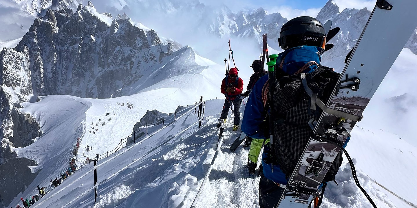 A line of people with skis strapped to their backs in chamonix