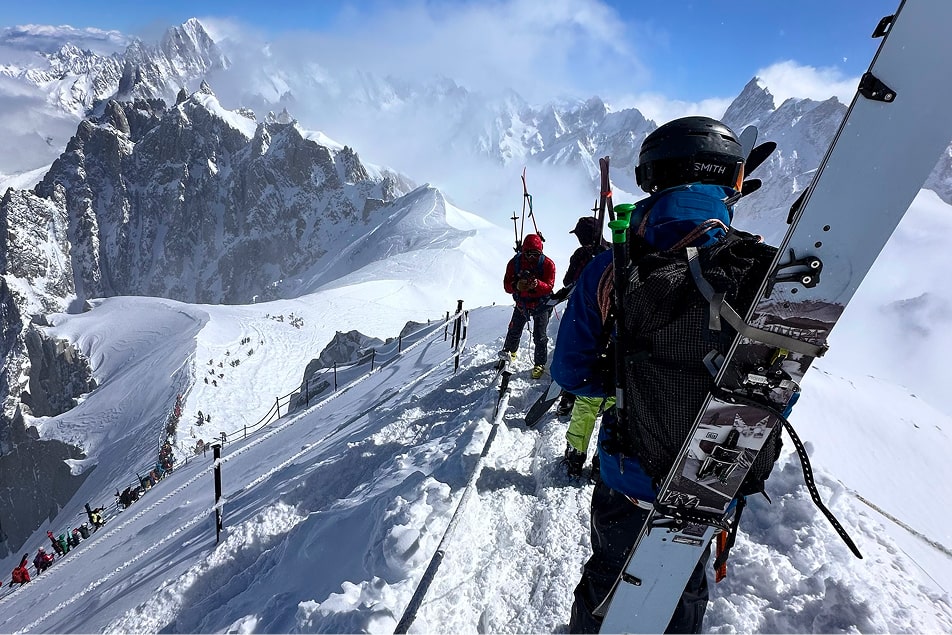 People with skis strapped to their backs in Chamonix