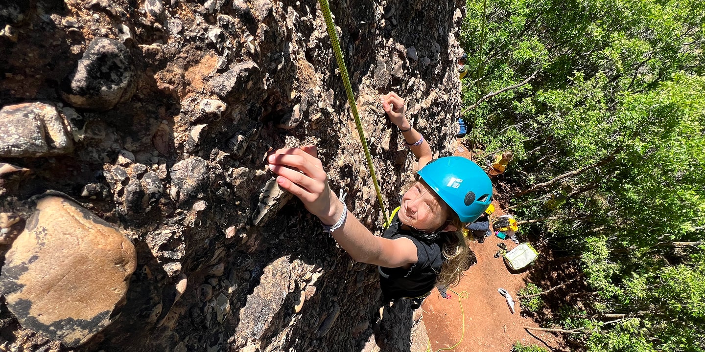 A girl in a blue helmet rock climbing