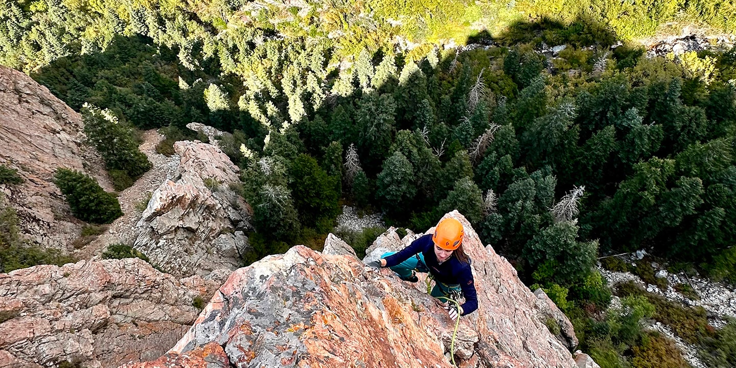 A person in an orange helmet rock climbing